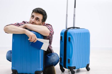 Gecikmiş uçak konsepti. Yorgun yolcu havaalanı terminalinde bavulunda uyuyor ve uçağın gelişini bekliyor..