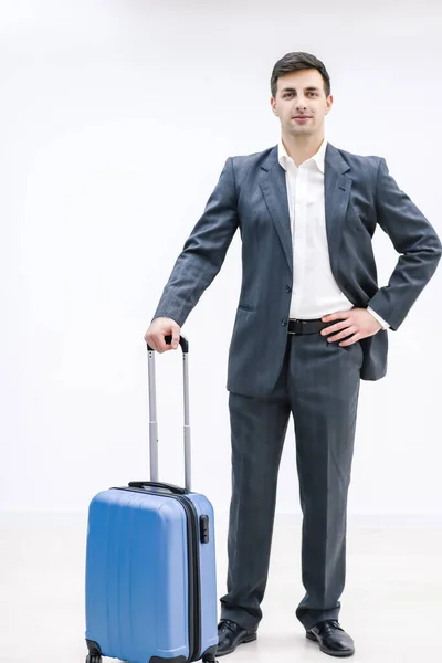 Młody przystojny biznesmen w garniturze, przychodzi z walizką, na posterunku, na lotnisku. — Zdjęcie stockowe