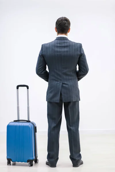 Achteraanzicht van succesvolle zakenman in pak in luchthaventerminal, met koffer over witte achtergrond. — Stockfoto