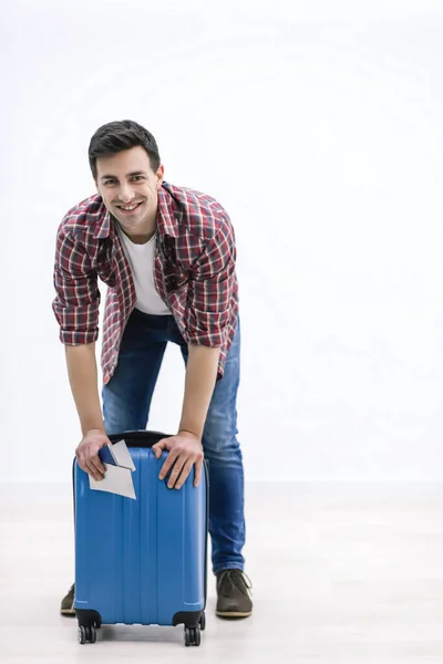 Zdjęcie szczęśliwego młodego człowieka gotowego do podróży z walizką spakowaną na białym tle. — Zdjęcie stockowe
