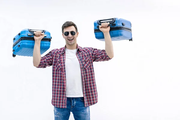 Молодой человек держит два голубых чемодана, в противовес новому назначению и приключениям . — стоковое фото