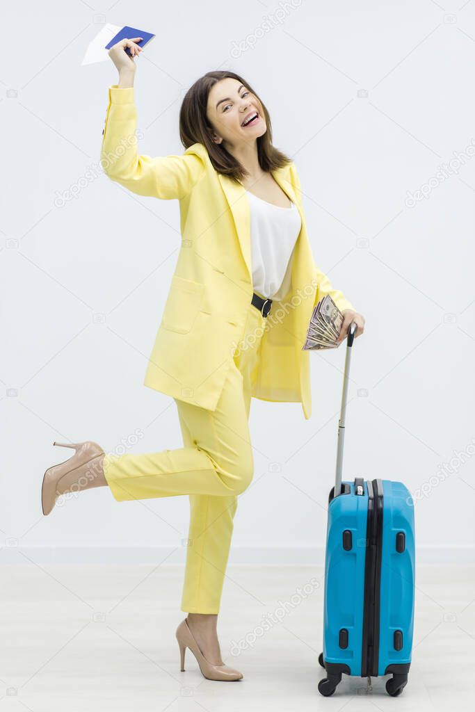 Cheerful young woman is dancing carrying a suitcase and passport, excited to go on a adventurous trip.