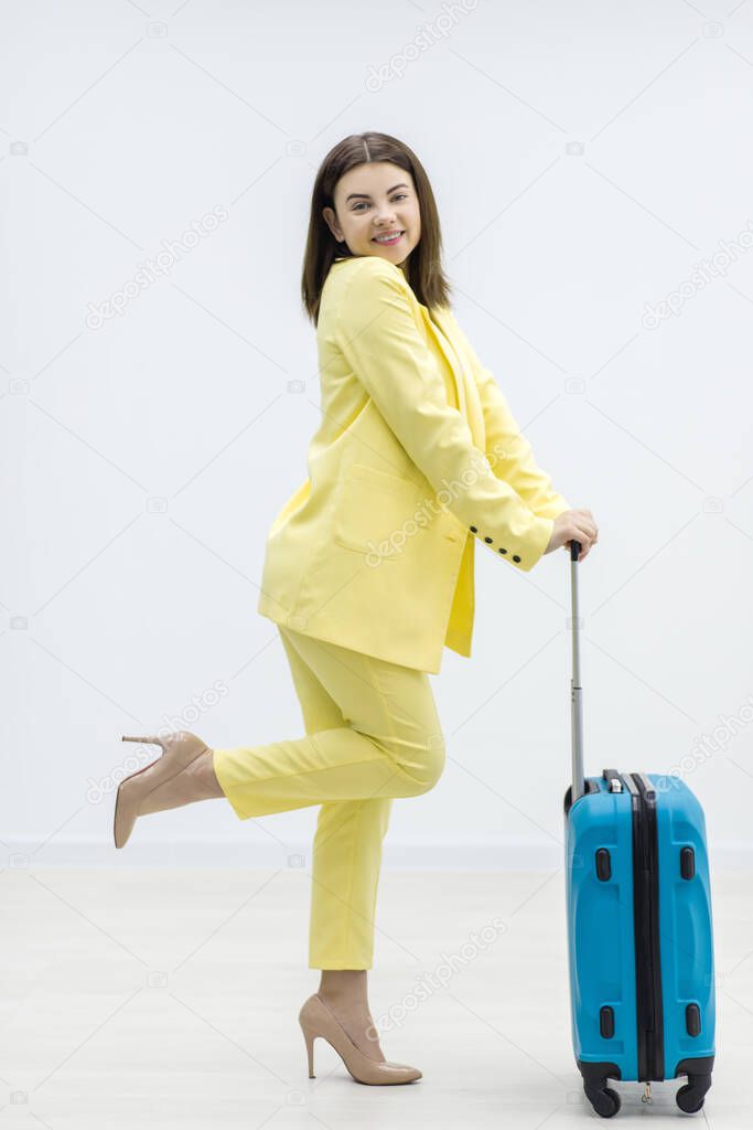 Cheerful young woman is dancing carrying a suitcase, excited to go on a adventurous trip.