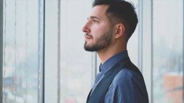 Resmi süitteki iş adamı şehir manzaralı panoramik pencerenin önünde duruyor. Profil görünümü. Dış profil. Kapatın. Animasyon. 4K.