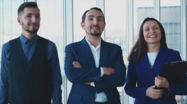Üç iş adamı çapraz kollarla ayakta duruyor. Kardinal gülümsemesi veriyorlar. Kapatın. Uzayı kopyala 4K.
