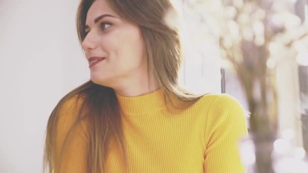 Adorable chica está sentada en la mesa en la cafetería. Ella es la comunicación con su novio hablador. El foco cae sobre el jarrón. De cerca. Copiar espacio . — Vídeos de Stock