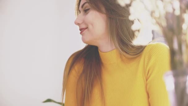 Adorable chica está sentada en la mesa en la cafetería. Ella es la comunicación con su novio, que muestra gestos. El foco cae sobre el jarrón. De cerca. Copiar espacio . — Vídeos de Stock