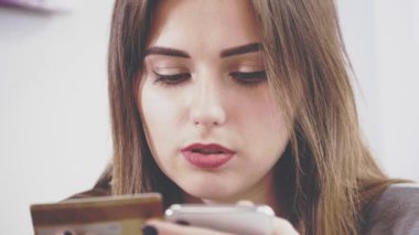 Sevimli kız kafedeki masada oturuyor. O, erkek arkadaşıyla iletişim kuruyor. Mutlu kız, sevgilisinin plastik kartlarını kullanarak internetten bir şeyler satın alıyor. Kapatın. Boşluğu kopyala.