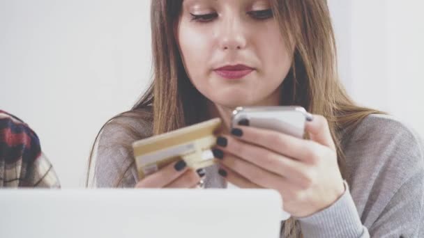 Adorabile ragazza è seduta a tavola nel caffè. Sta comunicando con il suo ragazzo. Ragazza felice sta comprando qualcosa via internet utilizzando i suoi fidanzati di plastica cardshopping. Chiudete. Copia spazio. — Video Stock