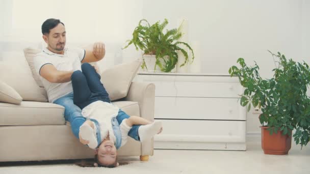4K zpomalení video, kde táta drží svou holčičku sedí na bílém gauči. — Stock video