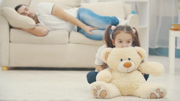 4k slowmotion video där lilla dotter spelar ensam medan pappa sover. — Stockvideo