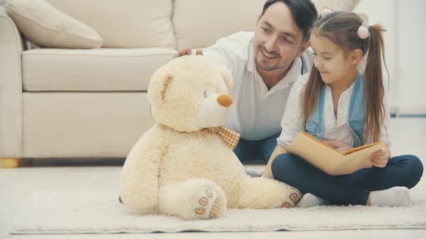 4k slow motion video donde linda niña leyendo un libro con su padre . — Vídeos de Stock