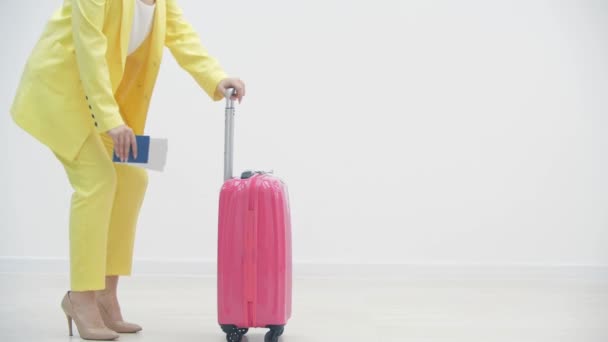 Młoda dziewczyna jest znudzona stojąc z walizką na lotnisku, ponieważ jej podróż została odwołana. — Wideo stockowe