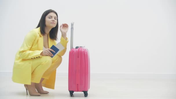 ビジネスマンは出張に行く。彼女は白い背景の上に彼女の側のパスポートと青いスーツケースと立っている. — ストック動画
