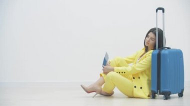 Yorgun iş kadını bavulun üzerine uzanıp bir havaalanı salonunda uyuyor..