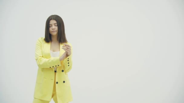 Pretenziosa donna bruna in abito formale giallo applaudendo, e guardando infastidito su sfondo bianco — Video Stock