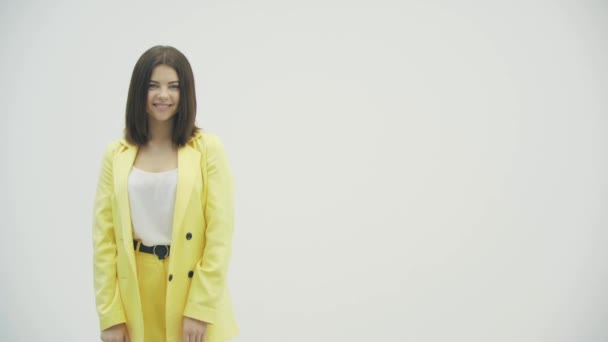 Vidéo 4k de femme souriante envoie un baiser d'air à la caméra posant sur fond blanc. — Video