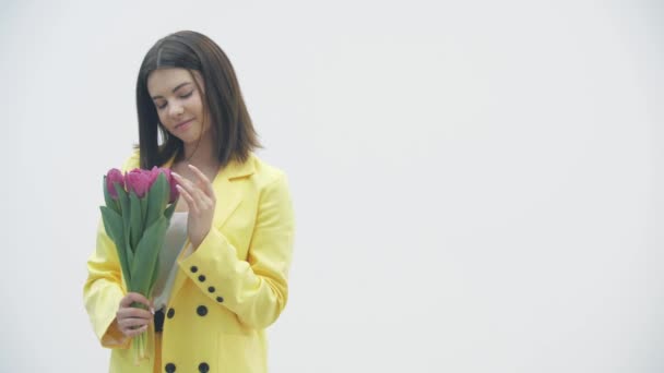 Молодая женщина наслаждается букетом тюльпанов на белом фоне . — стоковое видео
