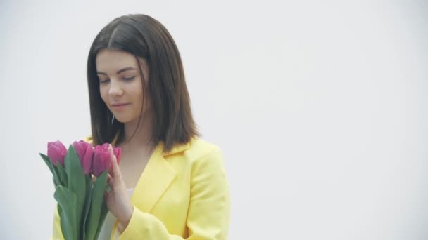 Jovem fêmea desfrutando de um buquê de tulipas sobre fundo branco . — Vídeo de Stock