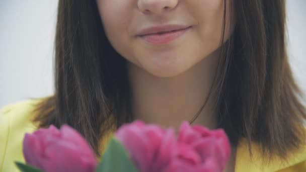 Przycięte 4k wideo młodej kobiety wąchającej bukiet tulipanów na białym tle. — Wideo stockowe