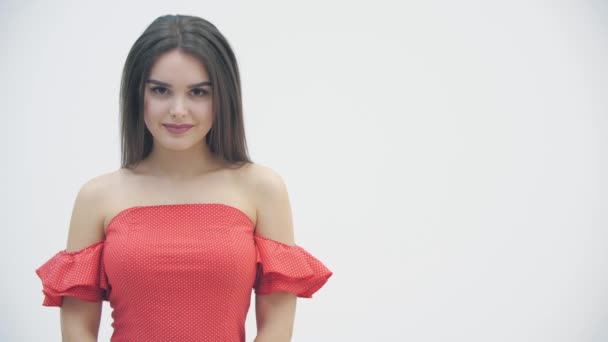 Closeup lentidão de atraente menina bonita em um vestido vermelho com ombros nus posando sobre fundo branco . — Vídeo de Stock