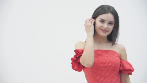 Movimiento lento de la joven mujer magnífica posando en vestido rojo de moda sobre fondo blanco . — Vídeo de stock
