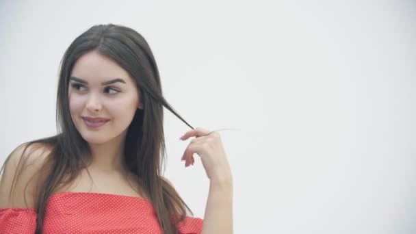 Movimiento lento de la joven mujer magnífica posando en vestido rojo de moda sobre fondo blanco . — Vídeos de Stock