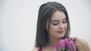 Pembe lale kokan, kameraya hafifçe gülümseyen, barışçıl görünen genç bir kadının yavaş çekim videosu..