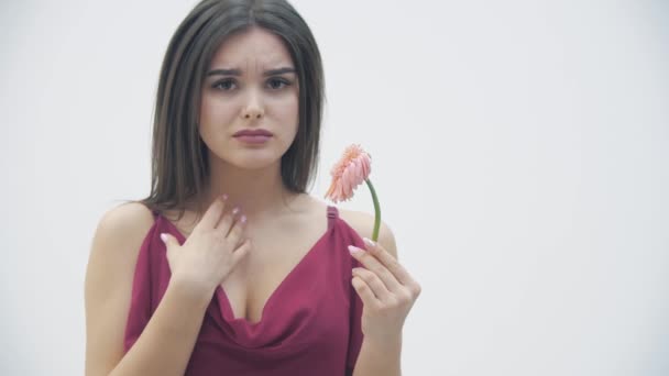 Eine Frau hält trockene Blumen in der Hand und betrachtet sie mit Kummer vor weißem Hintergrund. — Stockvideo