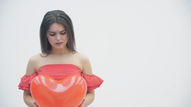 4k видео расстроенной девушки держит красный сердечный шар, думая о безответной любви или расставании . — стоковое видео