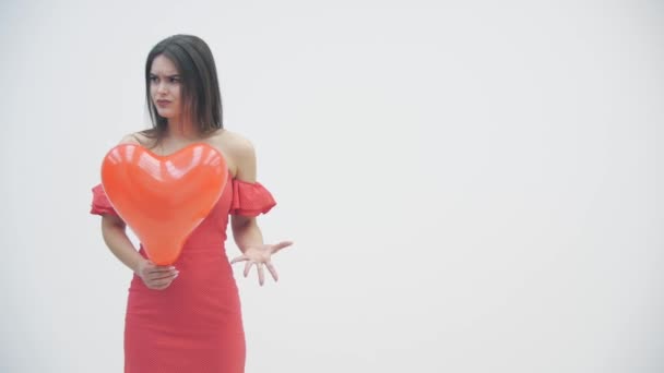 4k video gadis marah memegang balon jantung merah sambil berpikir tentang cinta tak berbalas atau perpisahan. — Stok Video