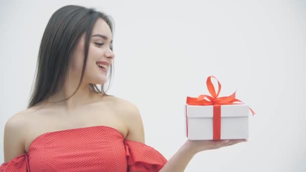 Video de una mujer alegre sosteniendo una caja de regalo y un globo de corazón, sonriendo sobre un fondo blanco . — Vídeo de stock