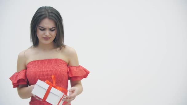 4k video de niña sosteniendo una caja de regalo, mirándolo con disgusto y luego lo deja caer . — Vídeos de Stock