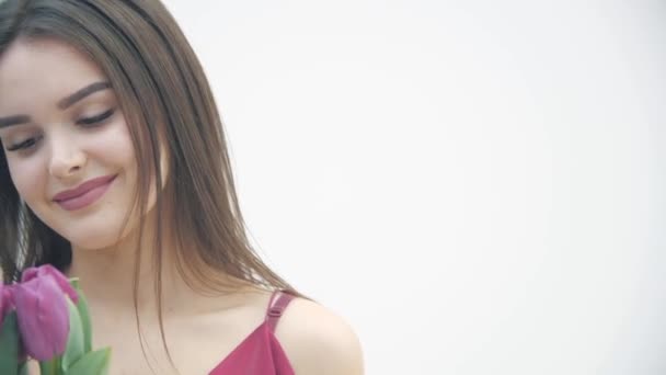 Close up 4k video de joven linda mujer oliendo tulipán rosa, ligeramente sonriendo a la cámara, buscando tranquilo . — Vídeo de stock