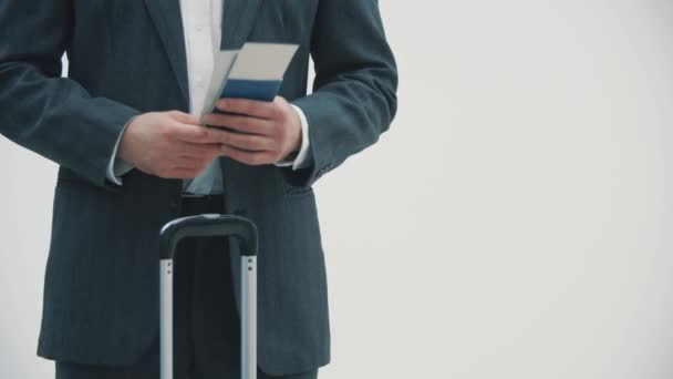 Περικοπή βίντεο βραδείας κίνησης ενός καυκάσιου επαγγελματία ταξιδιώτη με βαλίτσα και ταξιδιωτικά έγγραφα σε λευκό φόντο. — Αρχείο Βίντεο