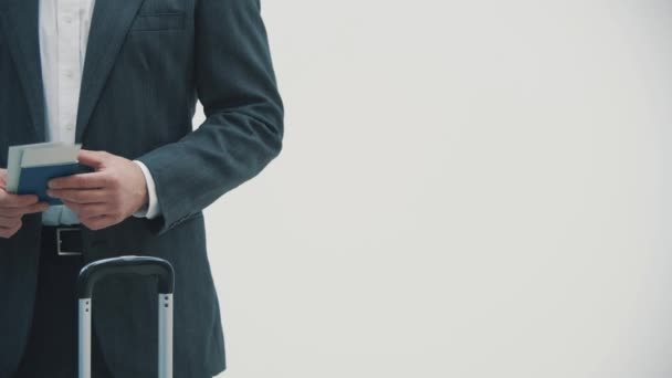 Cropped slowmotion video of one caucasian business traveler with suitcase and travel documents over white background. — Stock Video