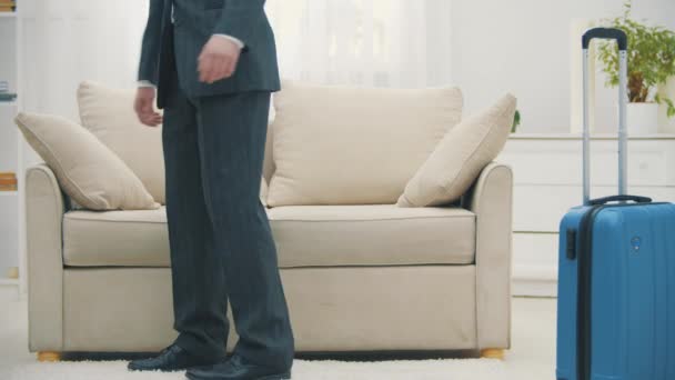 Homme arrivant à la chambre d'hôtel avec valise et assis sur le canapé l'air très fatigué. — Video