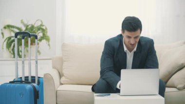 Genç adamın uçak biletleri için dizüstü bilgisayar kullanması ya da evde online check-in yapması..