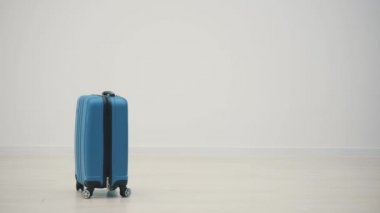 Beyaz arkaplanda mavi bir bavulu gösteren yavaş çekim videosu.