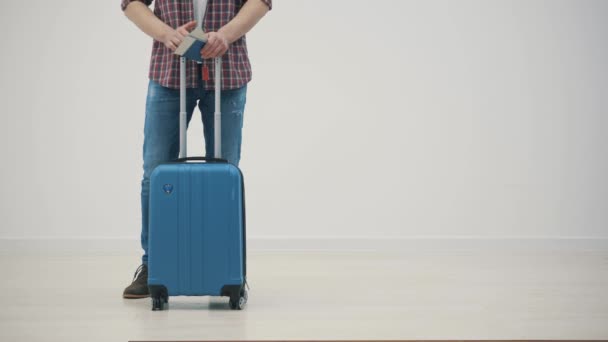 Ausschnittsweise Zeitlupe eines glücklichen jungen Mannes, der mit seinem Koffer vor weißem Hintergrund bereit für die Reise ist. — Stockvideo