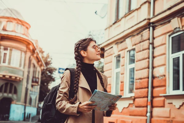 Lovely tourist got lost in a foreign city and looks at a map to find way out.