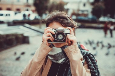 Genç bayan turist tatilde eski kasabayı ziyaret ediyor ve sokaktaki eski kameralarla fotoğraf çekiyor..