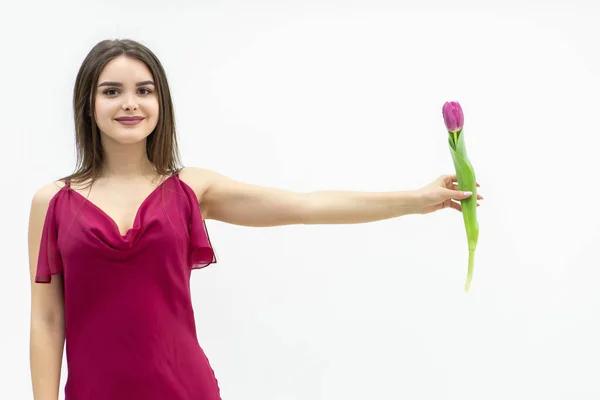 Tourné de jeune fille portant une robe marron et ressemblant à une fleur de tulipe qu'elle tient à la main sur fond blanc. — Photo