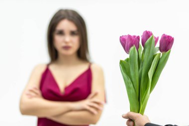 Kollarını kavuşturmuş üzgün, genç bir kadın. Ve lalelerden rahatsız olmuş görünüyor. Adam ona beyaz bir arka plan vermiş..