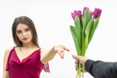 Züppe suratlı güzel bir kadın erkeğinin ona verdiği lalelere şüpheyle bakıyor..