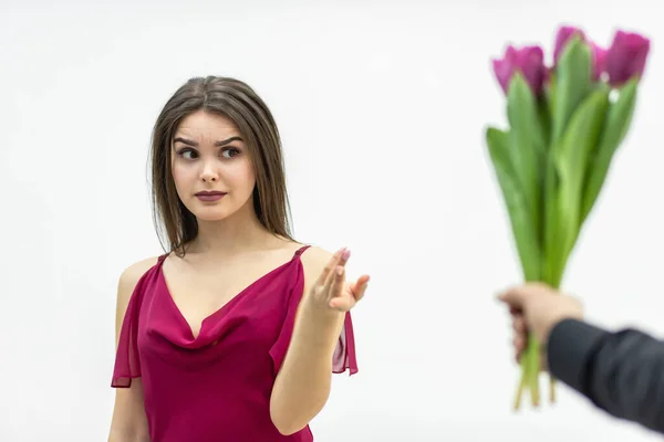 Belle femme à l'expression snob, regardant avec une expression sceptique le bouquet de tulipes que son homme lui donne. — Photo