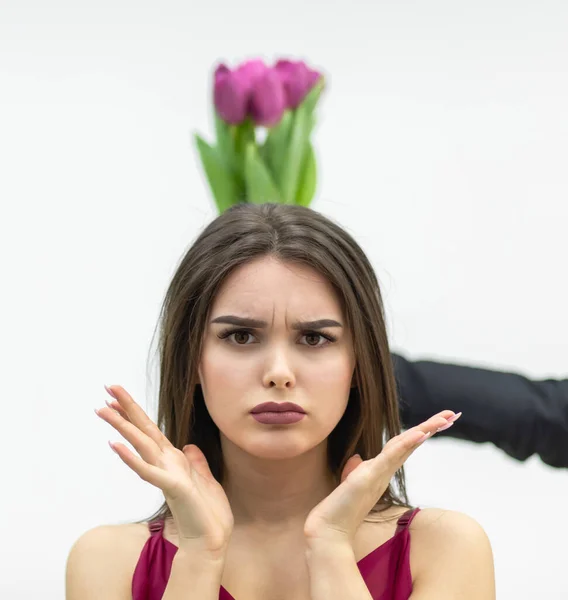 Belle femme avec une expression snob, regardant la caméra avec une expression sceptique tandis que son homme donne un tas de tulipes sur le dos. — Photo