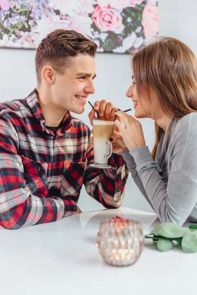 Vicces fiú és lány töltenek időt a kávézóban, viccelődnek és nevetnek kétségbeesetten, miközben kávét isznak egy pohárral szívószálból.. — Stock Fotó