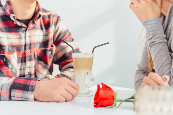 Tiro recortado de casal romântico curtindo a companhia uns dos outros, bebendo café do mesmo copo com palhas, sentado no café . — Fotografia de Stock