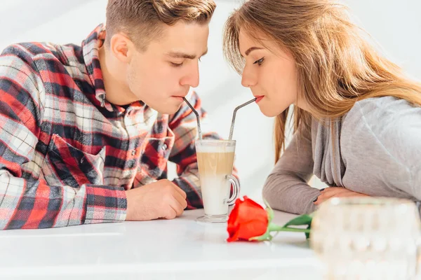 Обрізана жінка і чоловік в любові п'ють лате з соломинками з одного келиха, проводячи вільний час разом . — стокове фото